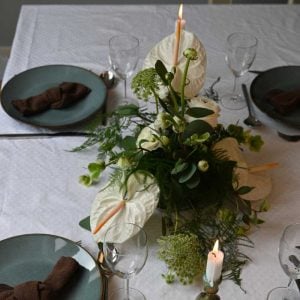 Hvid bordpynt med anthurium og andre blomster på bord