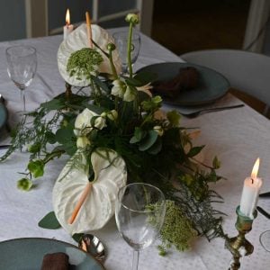 Hvid bordpynt med anthurium og andre blomster på bord