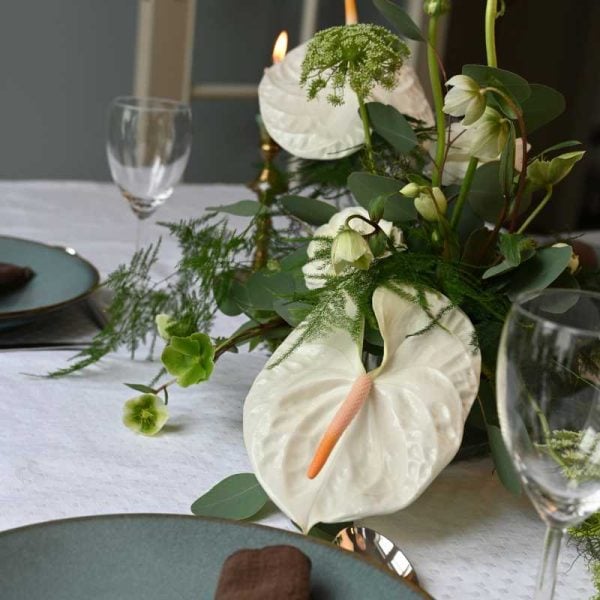 Hvid bordpynt med anthurium og andre blomster på bord