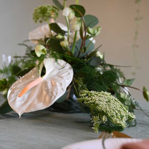 Hvid bordpynt med anthurium og andre blomster på bord