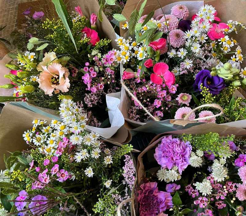 Fine buketter, der er pakket flot ind i brunt papir, så man stadigvæk kan se de mange farver på blomsterne..